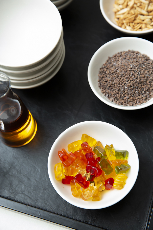 Gummibärchen in weisser Schale auf schwarzem Tablett